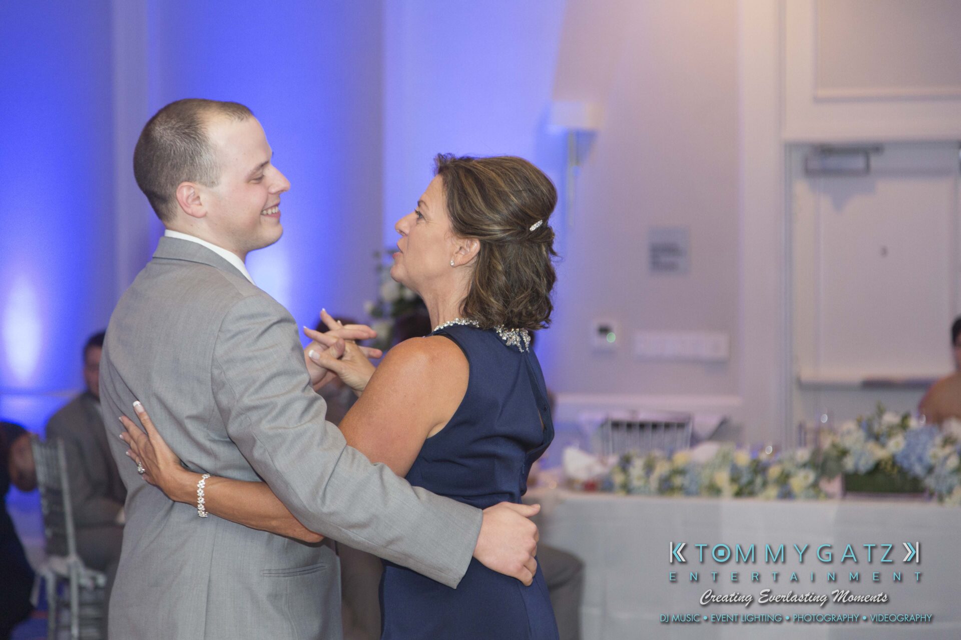Carly-Patrick-FINAL-Blog-Watermark-37 - TOMMY GATZ ENTERTAINMENT A man in a gray suit and a woman in a blue dress are dancing together at an event.