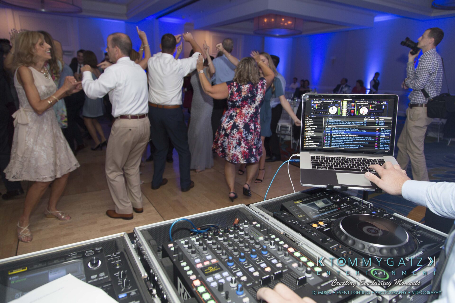 Carly-Patrick-FINAL-Blog-Watermark-39 - TOMMY GATZ ENTERTAINMENT People dancing energetically at an indoor event, with a DJ operating equipment in the foreground.