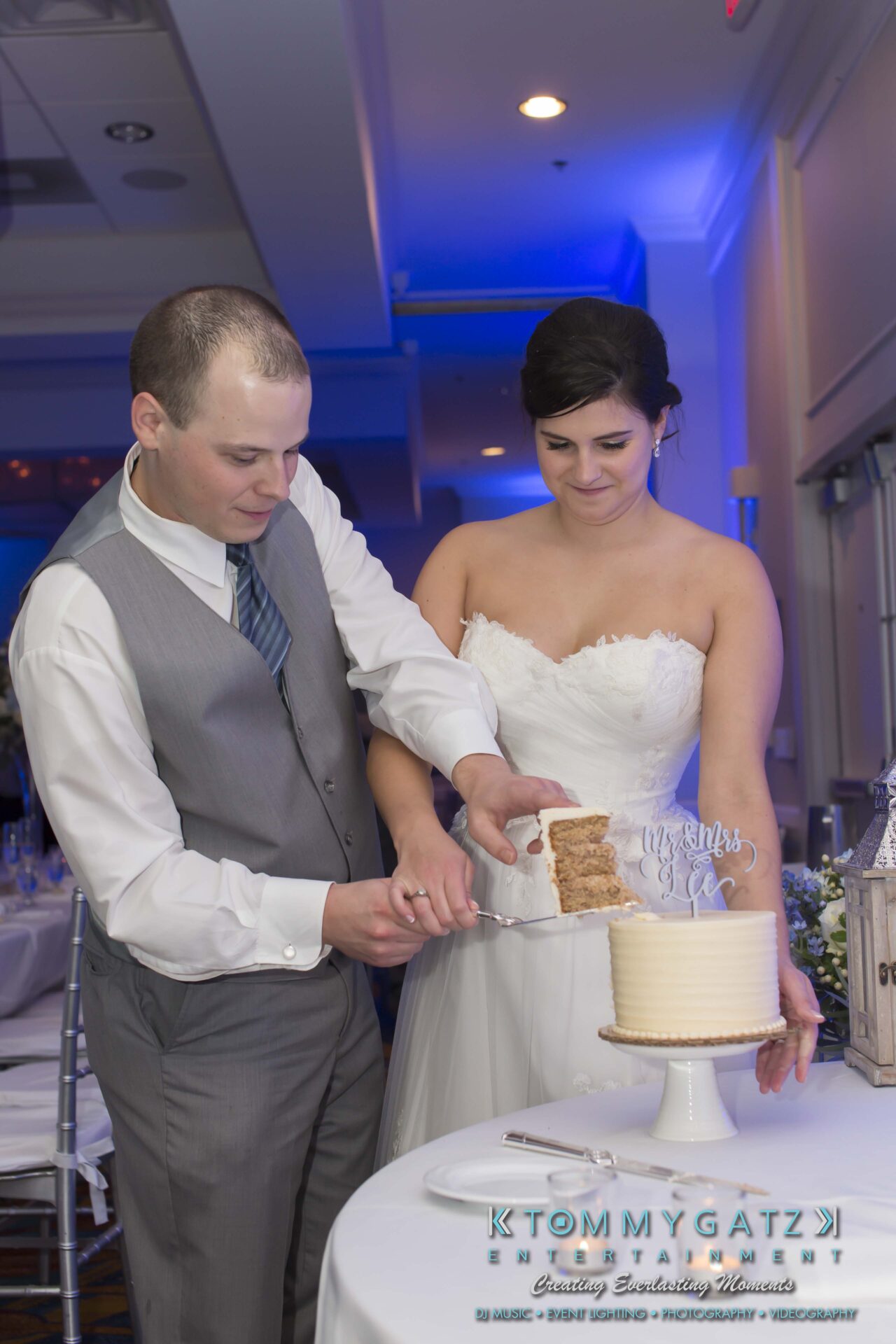 Carly-Patrick-FINAL-Blog-Watermark-43 - TOMMY GATZ ENTERTAINMENT A bride and groom cut a tiered wedding cake.