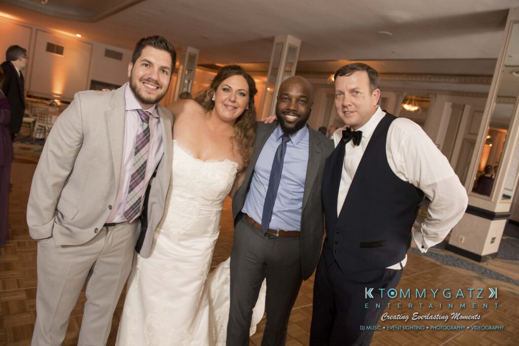 Elizabeth-Tom-101417-RECEPTION-Low-Res-WM-367 - TOMMY GATZ ENTERTAINMENT Four people pose together at an event; one is wearing a wedding dress, and the others are in formal attire.