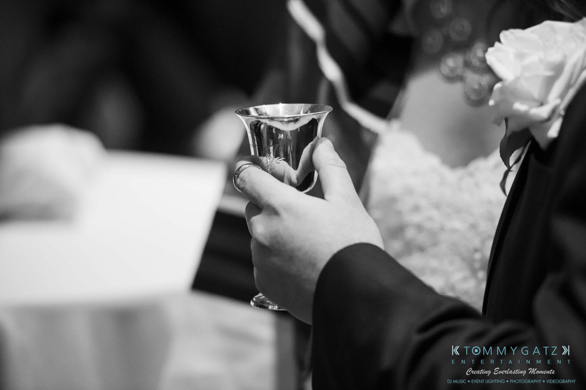 Person holding a silver cup during a formal event.