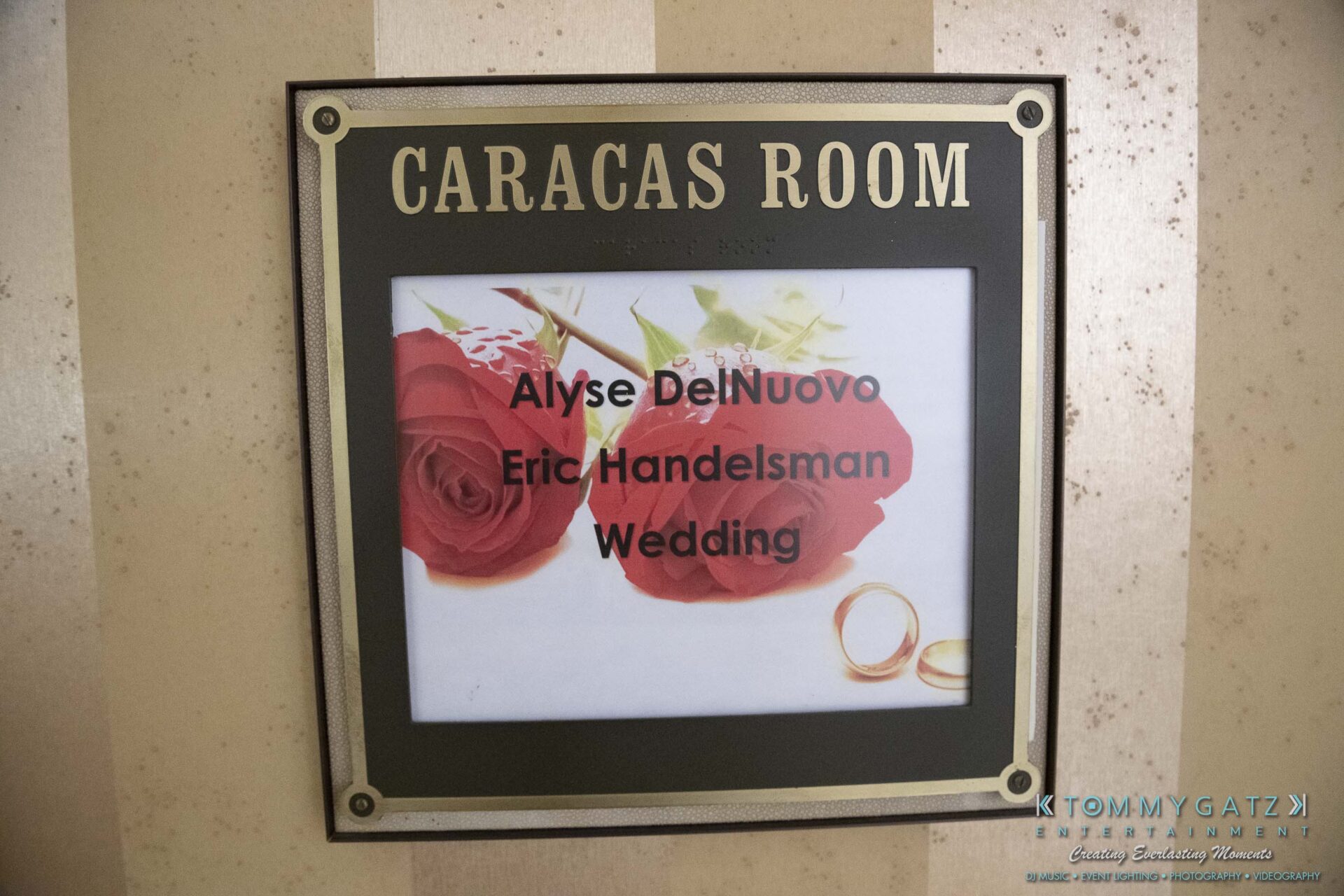 Wedding sign for Alyse DelNuovo and Eric Handelsman displayed in the Caracas Room, featuring roses and rings.