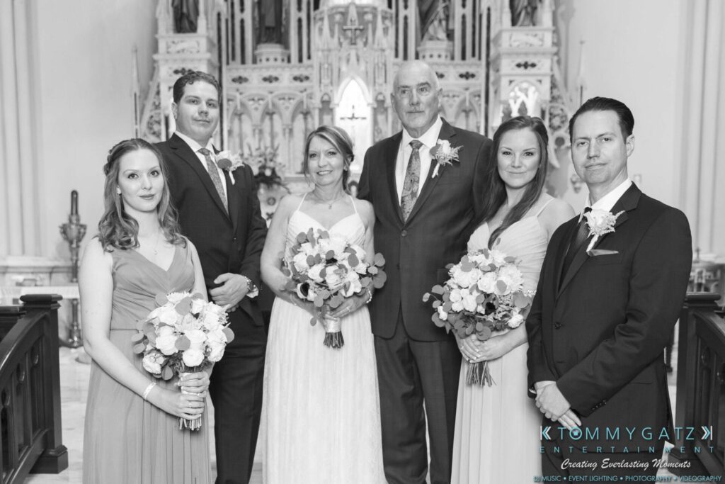 Grace-Michael-063018-FORMALS-Low-Res-WM-200 - TOMMY GATZ ENTERTAINMENT A wedding party poses in a church, featuring a bride, groom, two bridesmaids, and two groomsmen holding bouquets.