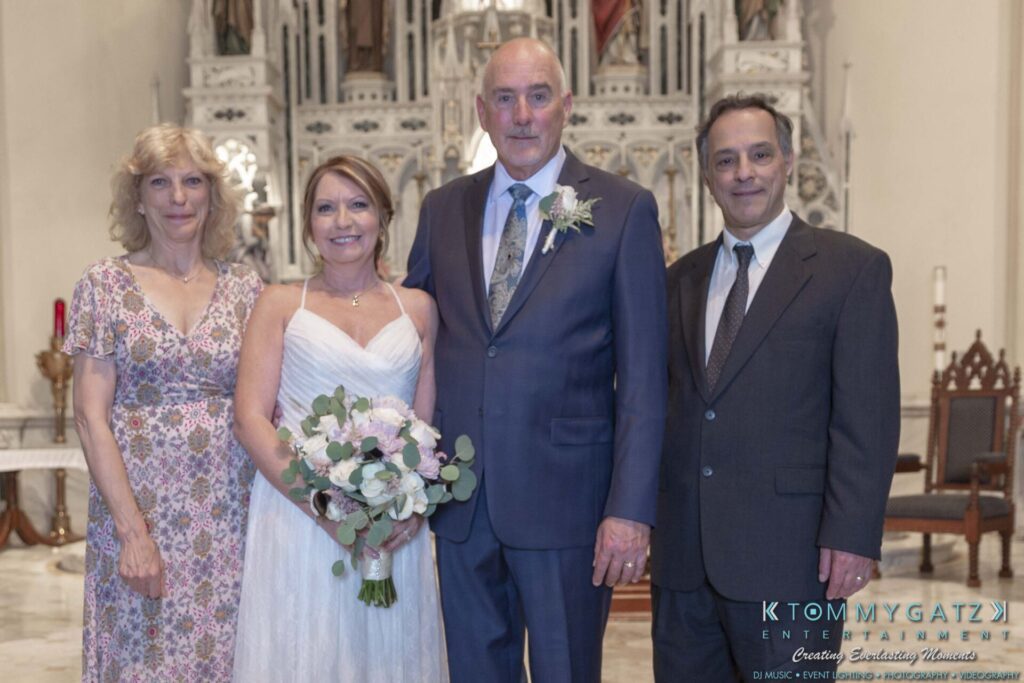 Four people standing together at a wedding, the bride holding a bouquet.