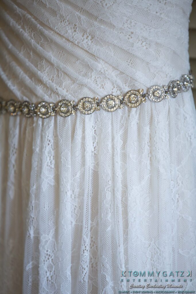 Close-up of a white lace dress with an ornate, circular silver belt detail.