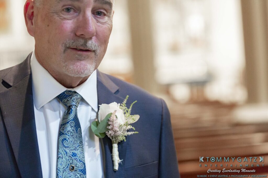 Grace-Michael-063018-PREP-Low-Res-WM-29 - TOMMY GATZ ENTERTAINMENT A man in a suit with a patterned tie and a boutonniere stands indoors.