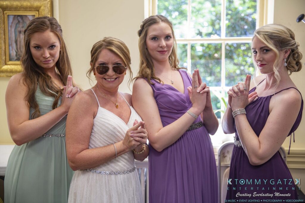 Grace-Michael-063018-PREP-Low-Res-WM-42 - TOMMY GATZ ENTERTAINMENT Four women in dresses pose playfully with finger-gun gestures. They're standing indoors in front of a window.