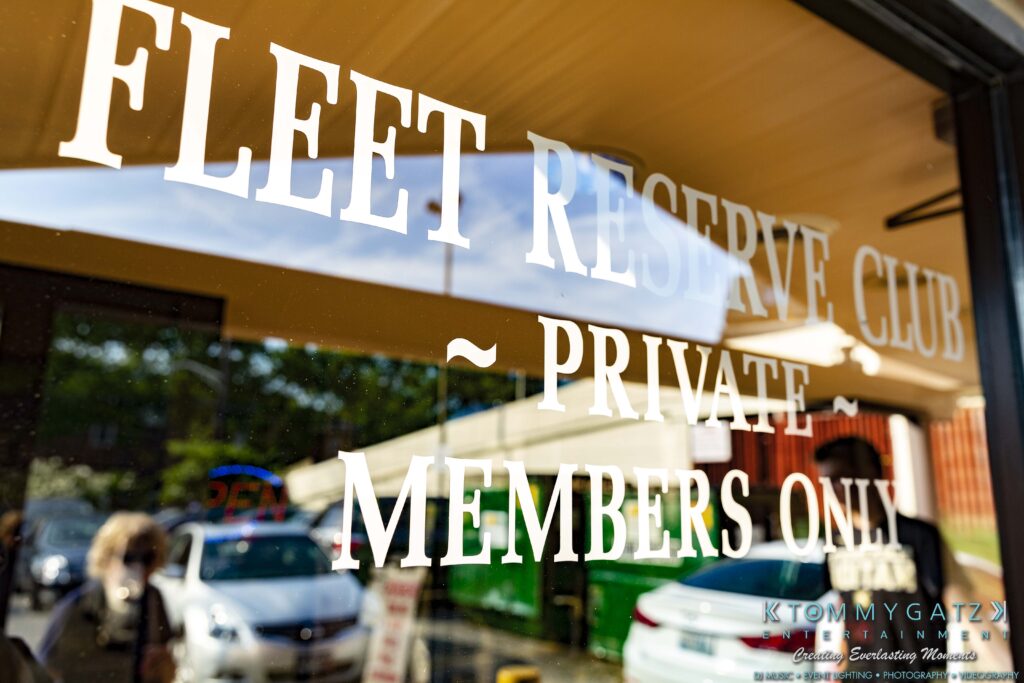 Grace-Michael-063018-RECEPTION-Low-Res-WM-345-1 - TOMMY GATZ ENTERTAINMENT Window with text reading "Fleet Reserve Club - Private - Members Only," reflecting a street scene with parked cars and a person visible.