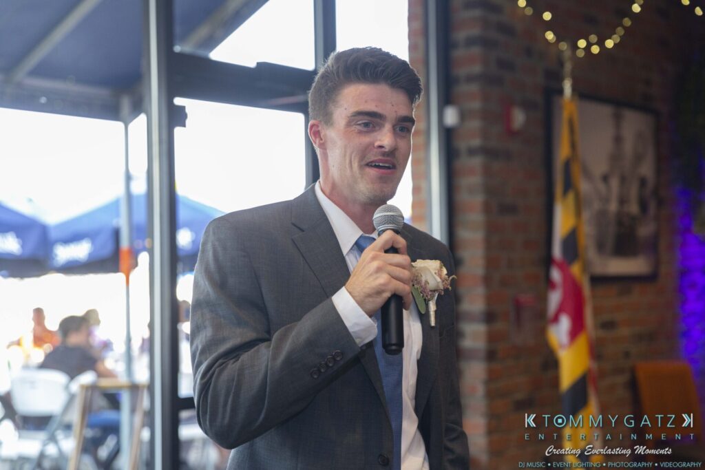 Grace-Michael-063018-RECEPTION-Low-Res-WM-371 - TOMMY GATZ ENTERTAINMENT A man in a suit speaks into a microphone at an indoor event.