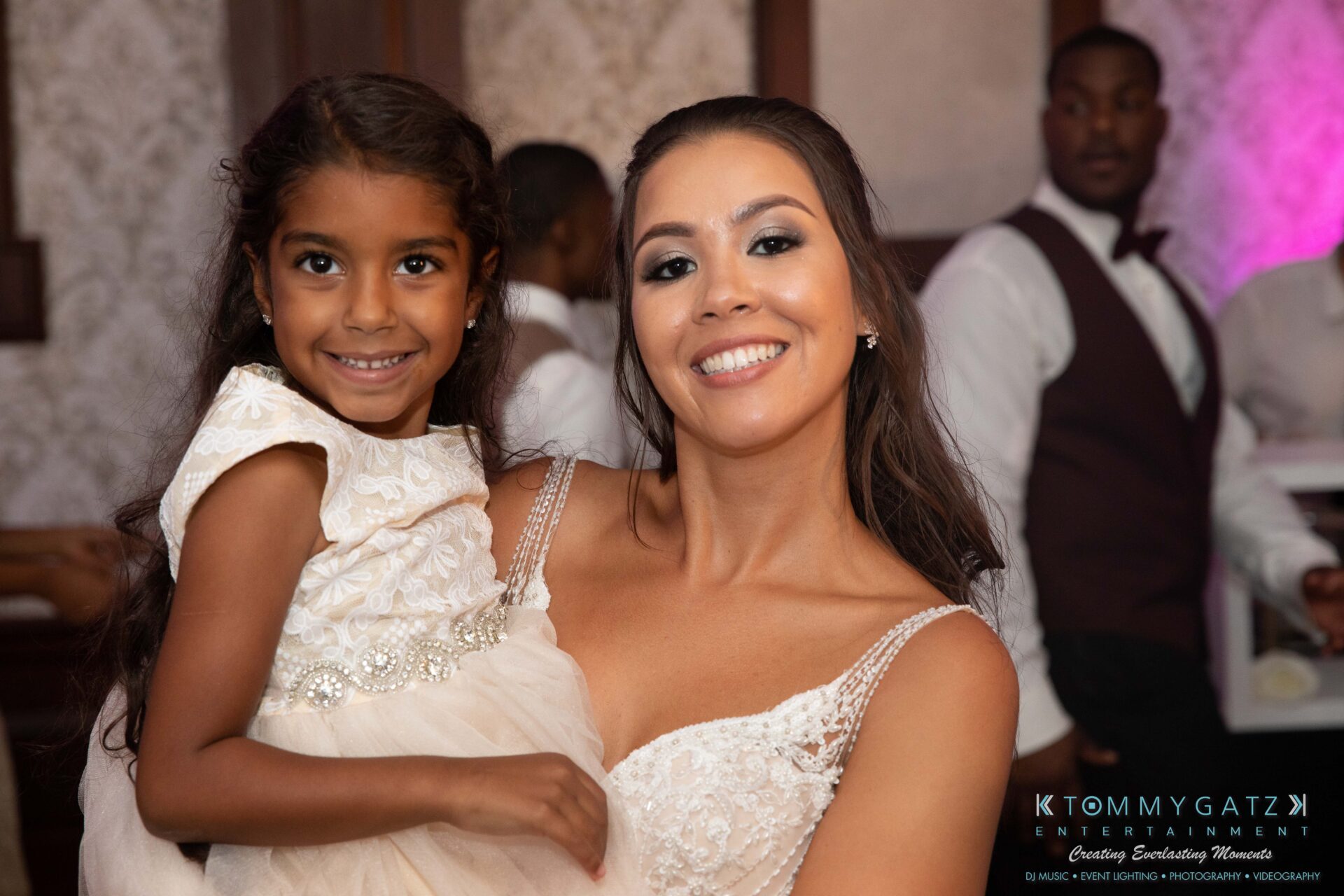 Harris-Wedding-HIGHLIGHTS-090119-106 - TOMMY GATZ ENTERTAINMENT A woman in a white dress poses with a smiling little girl wearing a white dress at an event.