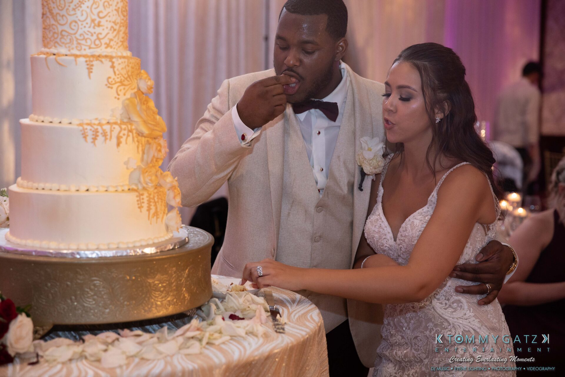 Harris-Wedding-HIGHLIGHTS-090119-122 - TOMMY GATZ ENTERTAINMENT A couple in formal attire feeds each other cake in front of a tiered wedding cake during a reception.