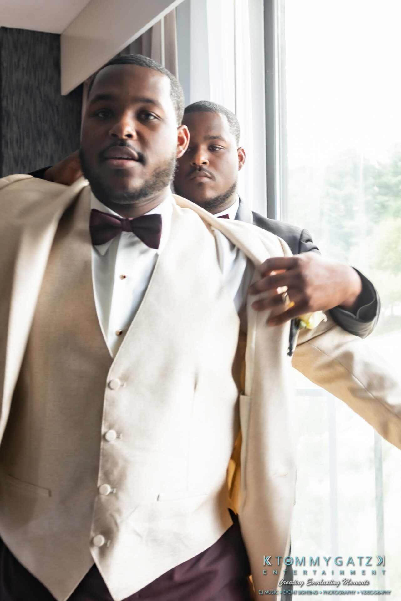 Harris-Wedding-HIGHLIGHTS-090119-42 - TOMMY GATZ ENTERTAINMENT Two men are dressing in formal wear near a window. One is adjusting the other's beige vest and jacket.