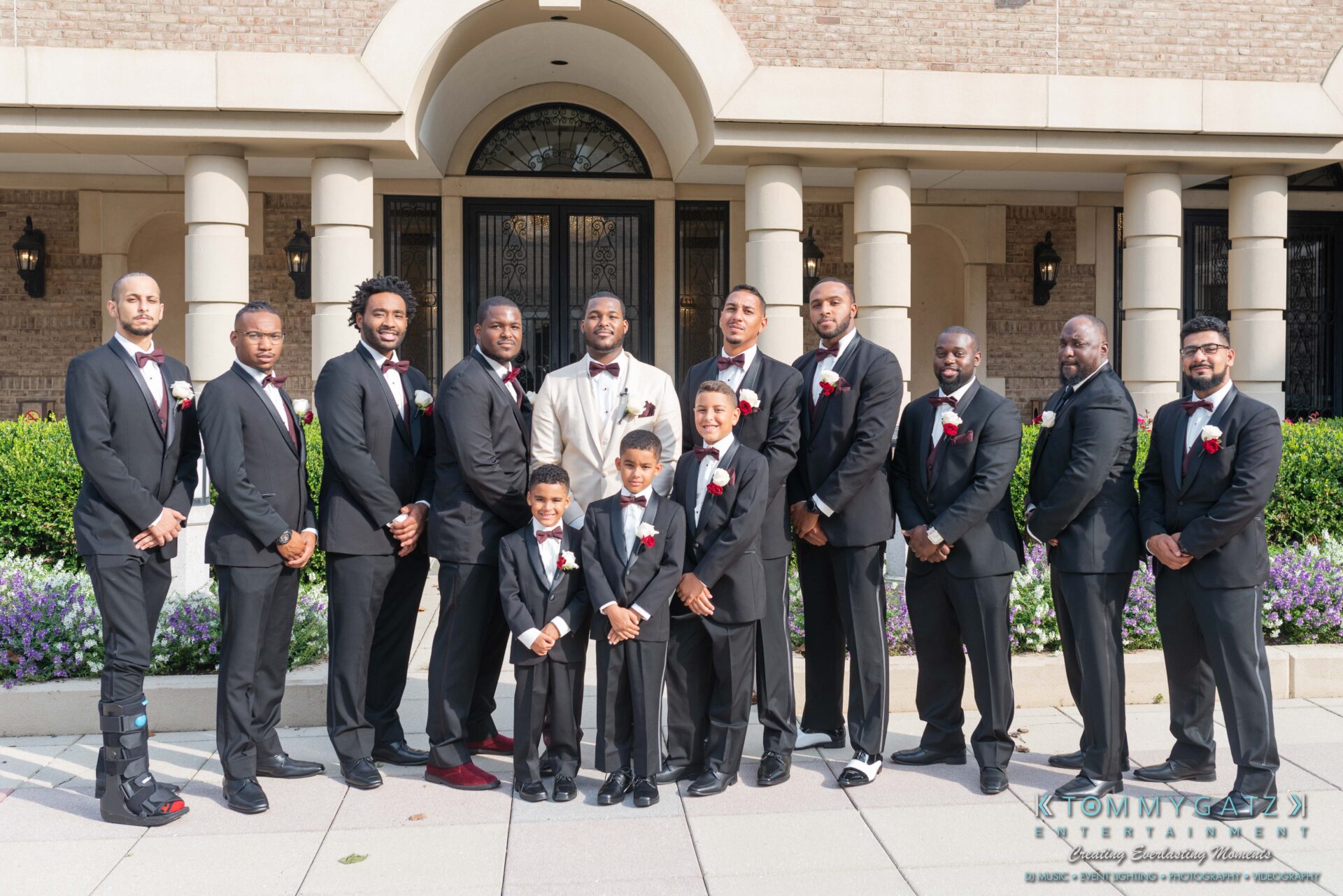 Harris-Wedding-HIGHLIGHTS-090119-59 - TOMMY GATZ ENTERTAINMENT A wedding party with twelve men and boys in formal suits, standing in front of a building entrance.