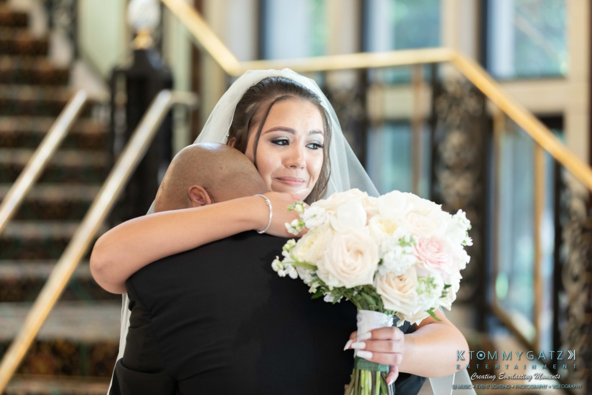 Harris-Wedding-HIGHLIGHTS-090119-67 - TOMMY GATZ ENTERTAINMENT A bride holding a bouquet hugs a man on a staircase, visibly emotional.