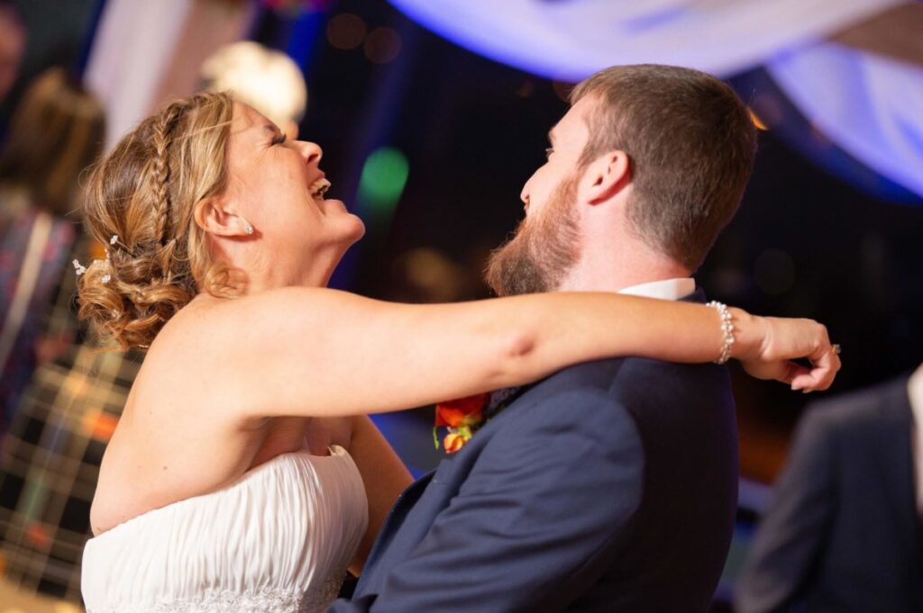 Heather-Scott-Wedding-Low-Res-120 1 - TOMMY GATZ ENTERTAINMENT A bride and groom joyfully dance together at their wedding reception.