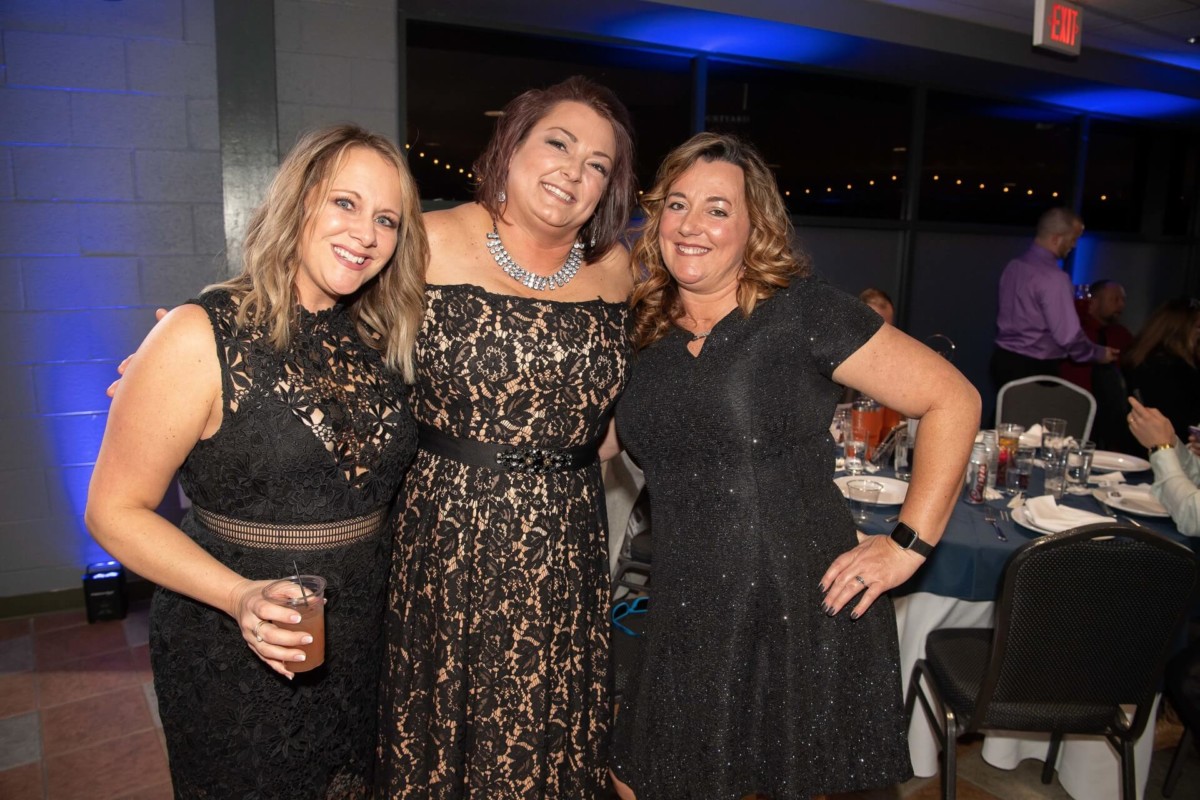 Heather-Scott-Wedding-Low-Res-126 1 - TOMMY GATZ ENTERTAINMENT Three people in black dresses pose together at a formal event, smiling at the camera.
