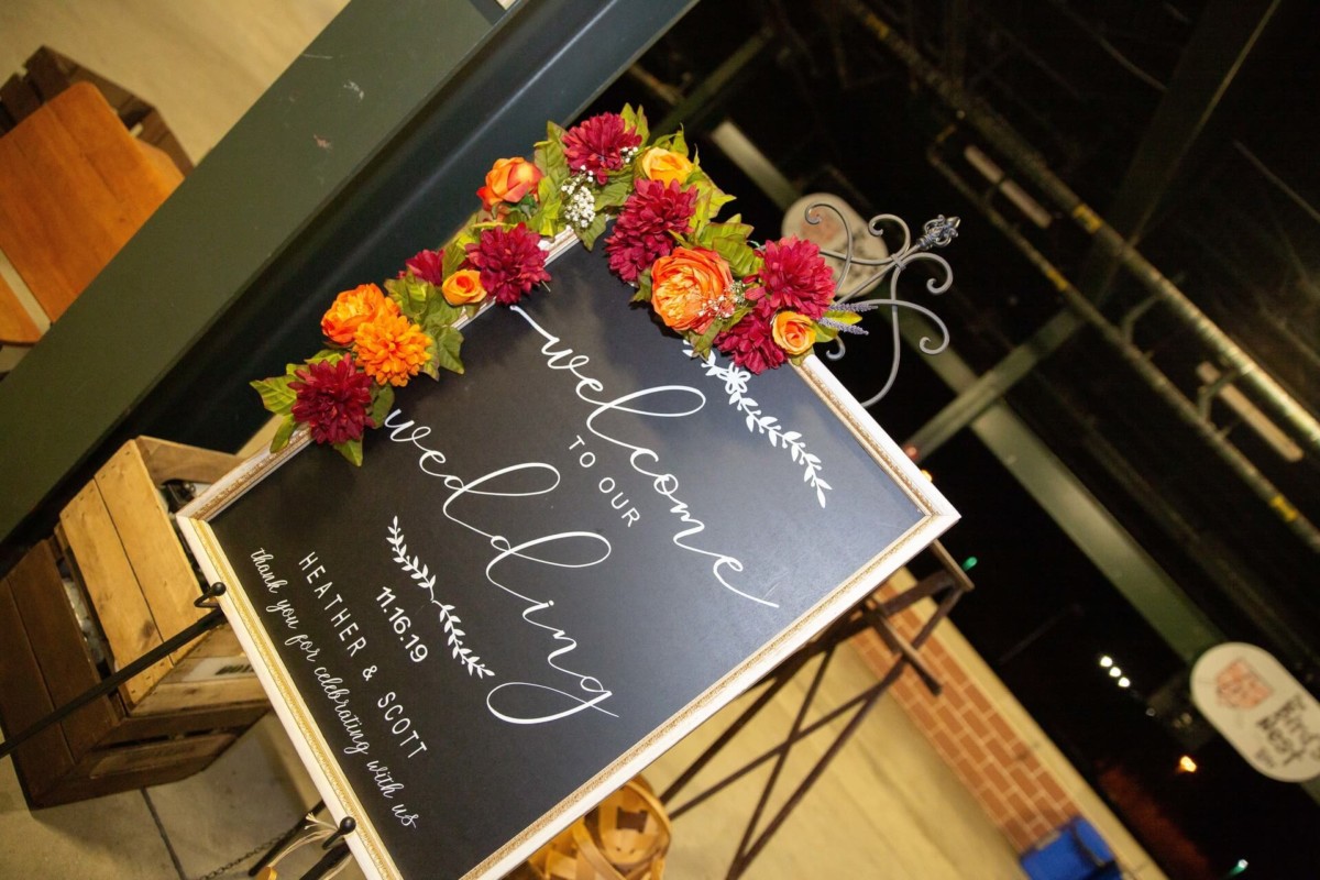 Heather-Scott-Wedding-Low-Res-137 1 - TOMMY GATZ ENTERTAINMENT Wedding welcome sign with floral decorations reads, "Welcome to our wedding. Heather & Scott.