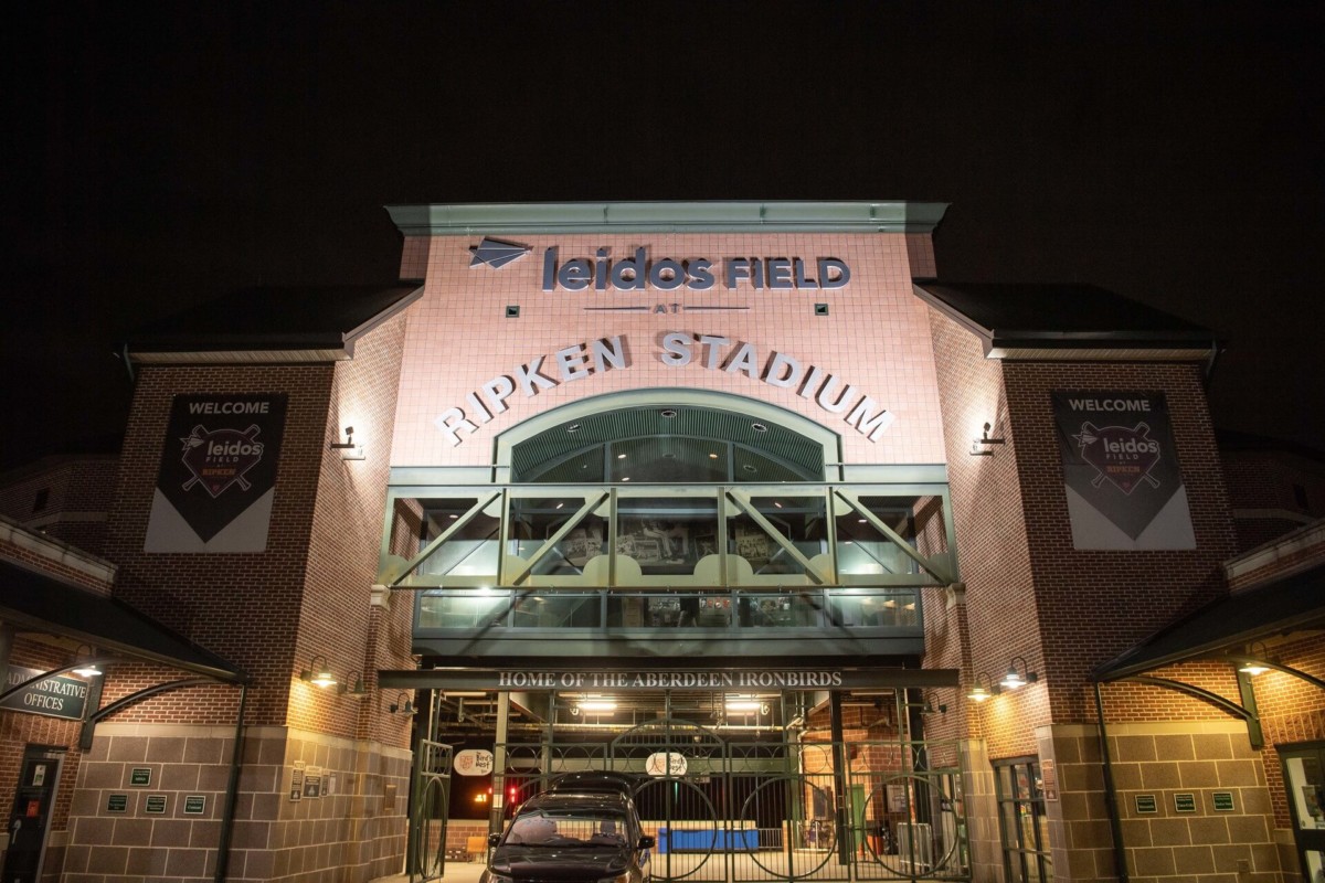 Heather-Scott-Wedding-Low-Res-153 1 - TOMMY GATZ ENTERTAINMENT Nighttime view of Leidos Field at Ripken Stadium entrance, illuminated with signs welcoming visitors, featuring brick walls and a central arched design.