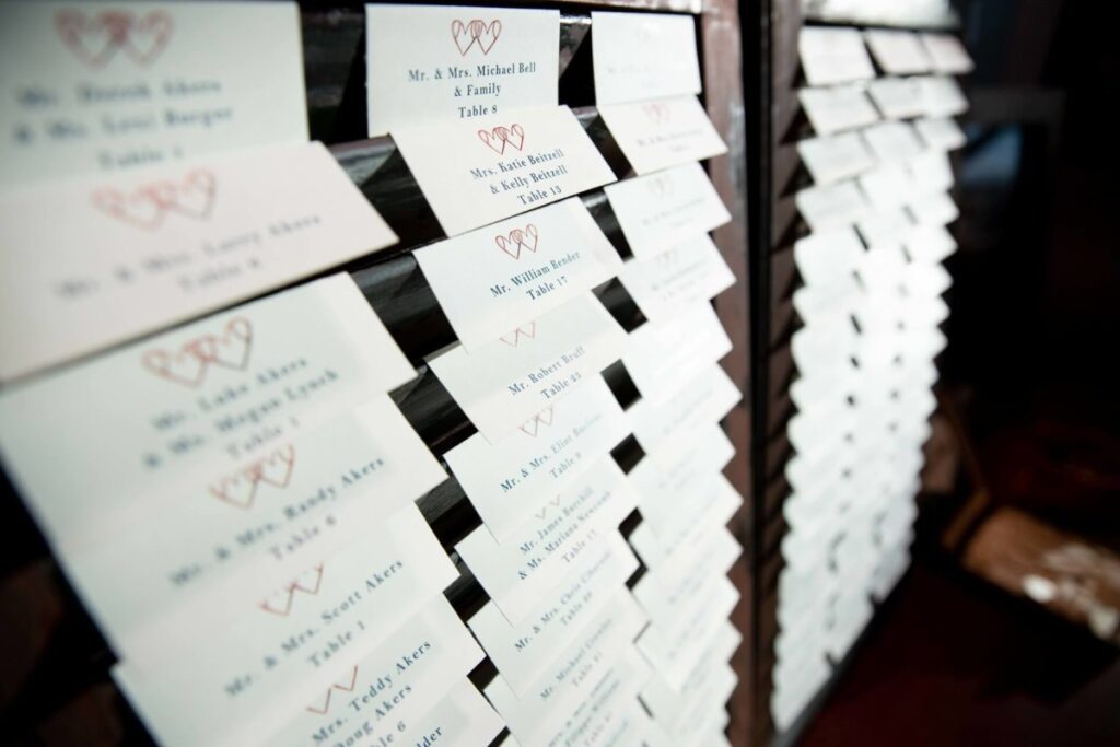 Heather-Scott-Wedding-Low-Res-56 1 - TOMMY GATZ ENTERTAINMENT Table place cards organized in rows on a display board with names and table numbers.