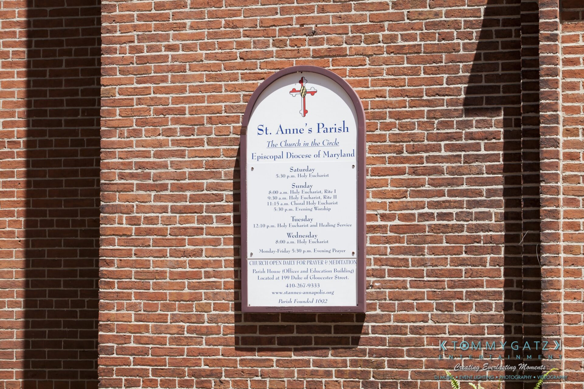 Jamie-and-Mark-Low-Res-Watermark-22 - TOMMY GATZ ENTERTAINMENT Sign for St. Anne's Parish, Episcopal Diocese of Maryland, on a brick wall. Lists service times and details.
