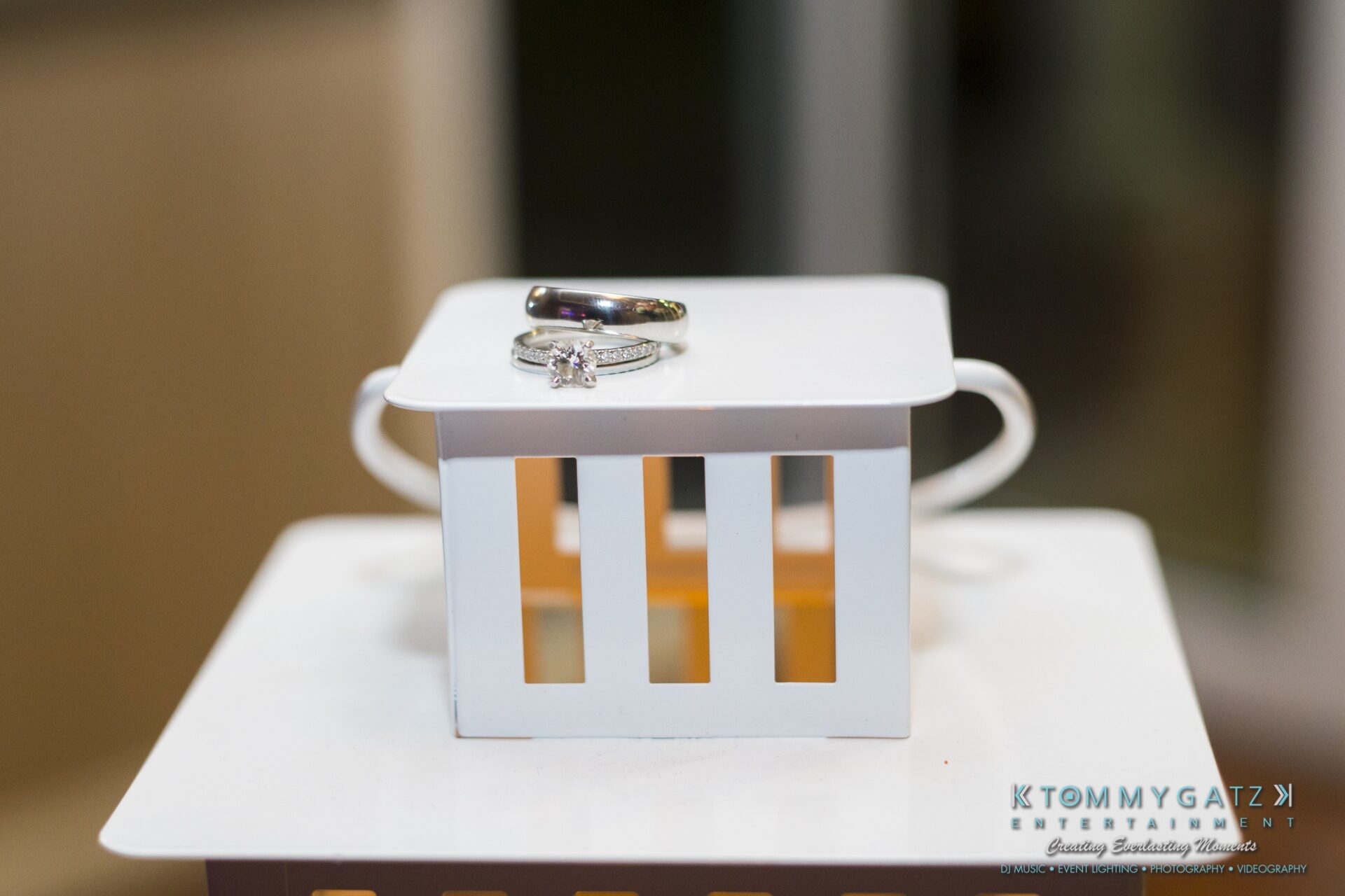 Jamie-and-Mark-Low-Res-Watermark-781 - TOMMY GATZ ENTERTAINMENT A white box with a diamond ring and a black ring on top, placed on a larger white box.