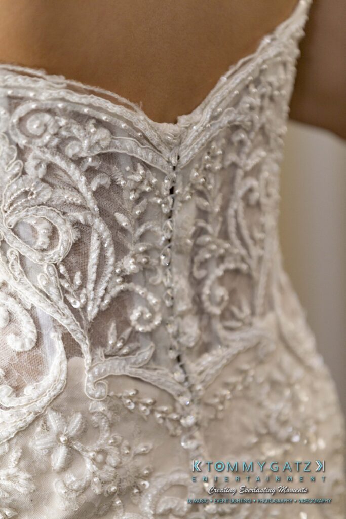 Close-up of an ornate, beaded wedding dress back with intricate lace patterns and decorative pearls.