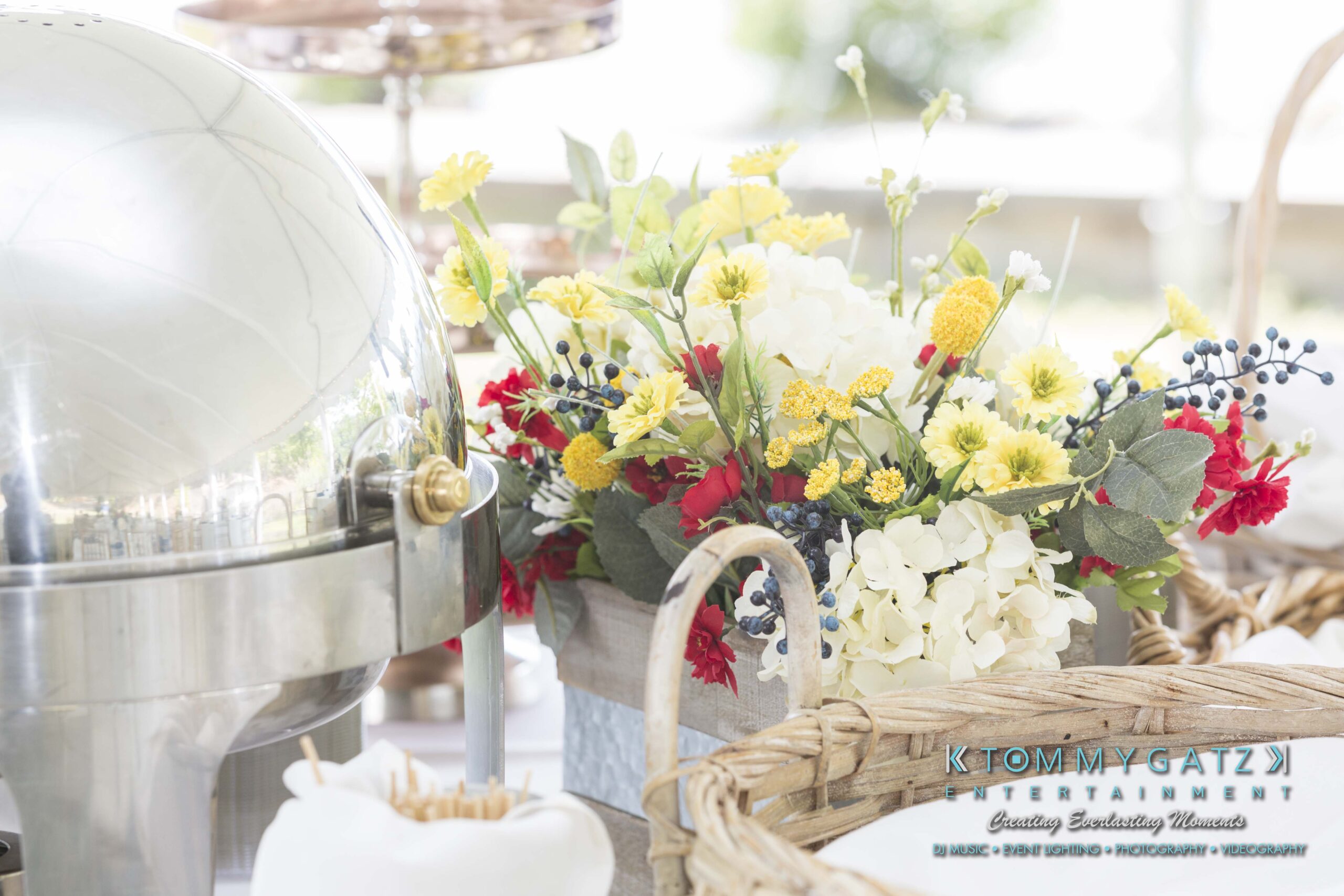 Keara-Patrick-Wedding-51218-FINALS-Low-Res-WM-4 - TOMMY GATZ ENTERTAINMENT Buffet setup with a metal food warmer, floral arrangement with yellow, red, and white flowers, and wicker baskets.
