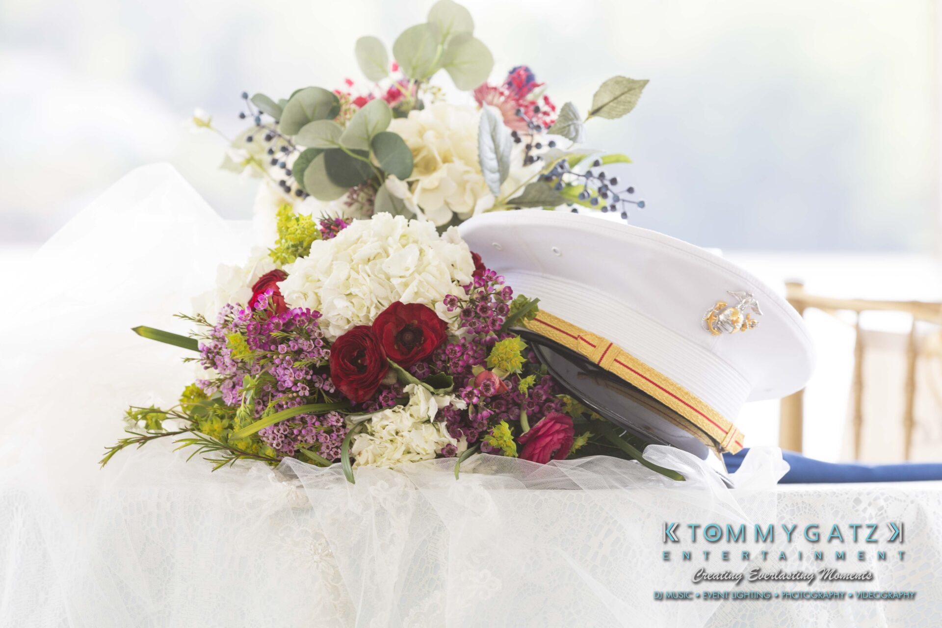 Keara-Patrick-Wedding-51218-FINALS-Low-Res-WM-8 - TOMMY GATZ ENTERTAINMENT A white military dress hat rests atop a bouquet of white, red, and purple flowers.