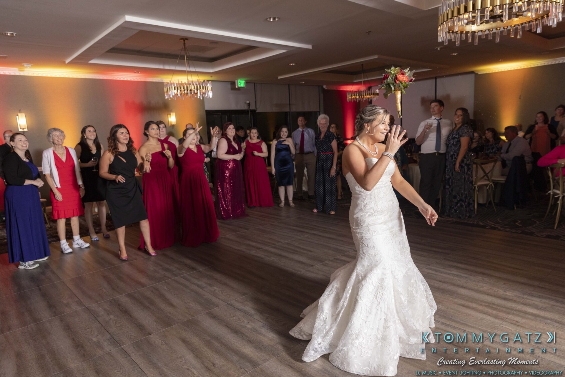 Lisa-Robert-092218-BLOG-selections-WM-100 - TOMMY GATZ ENTERTAINMENT A bride in a white gown prepares to toss her bouquet in front of a group of women in a reception hall.