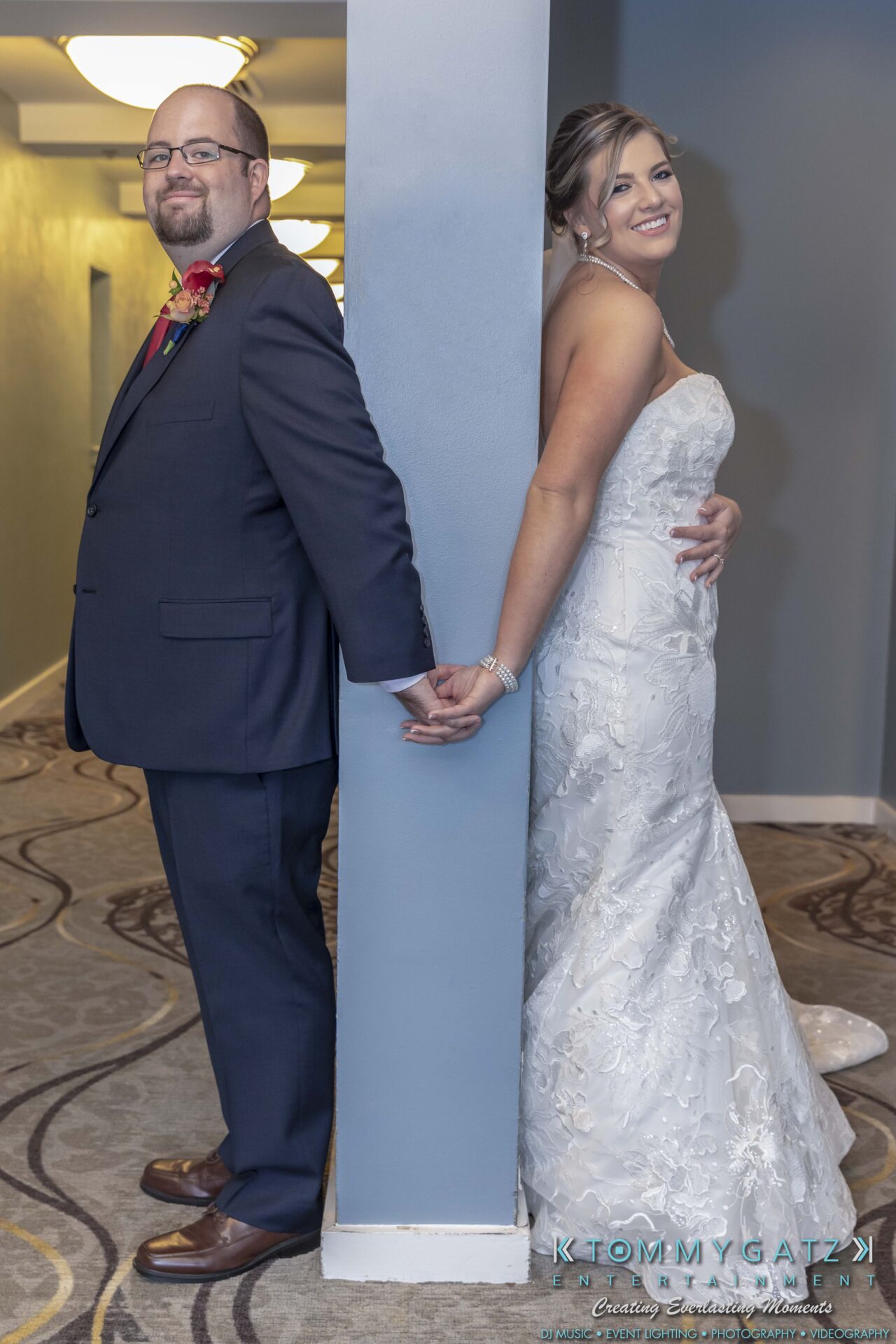 Lisa-Robert-092218-BLOG-selections-WM-35 - TOMMY GATZ ENTERTAINMENT Bride and groom stand back-to-back, holding hands around a corner. Bride wears a white dress; groom is in a dark suit.