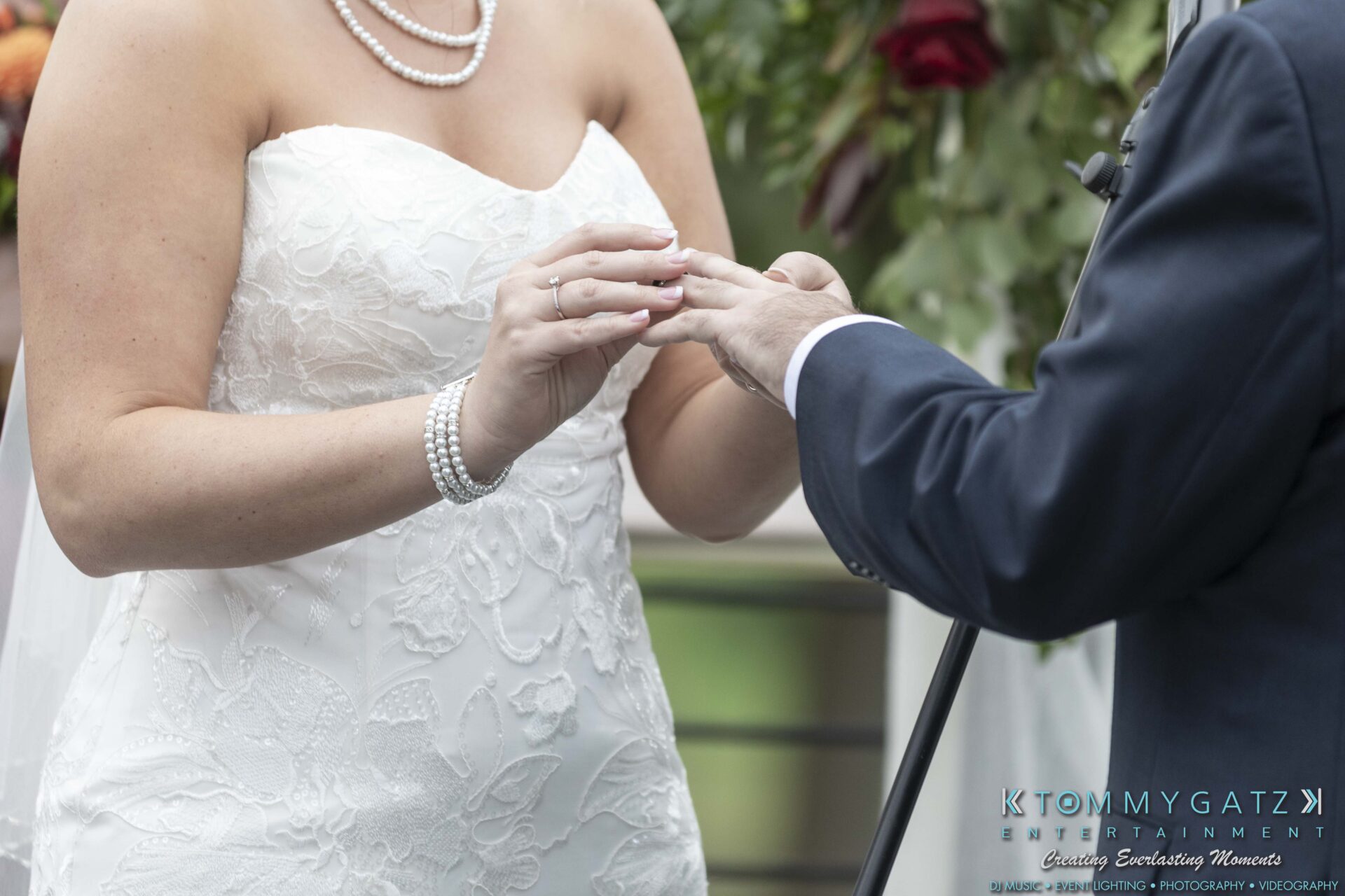 Lisa-Robert-092218-BLOG-selections-WM-56 - TOMMY GATZ ENTERTAINMENT Bride and groom exchanging rings during wedding ceremony, with bride in white lace dress and pearl jewelry.