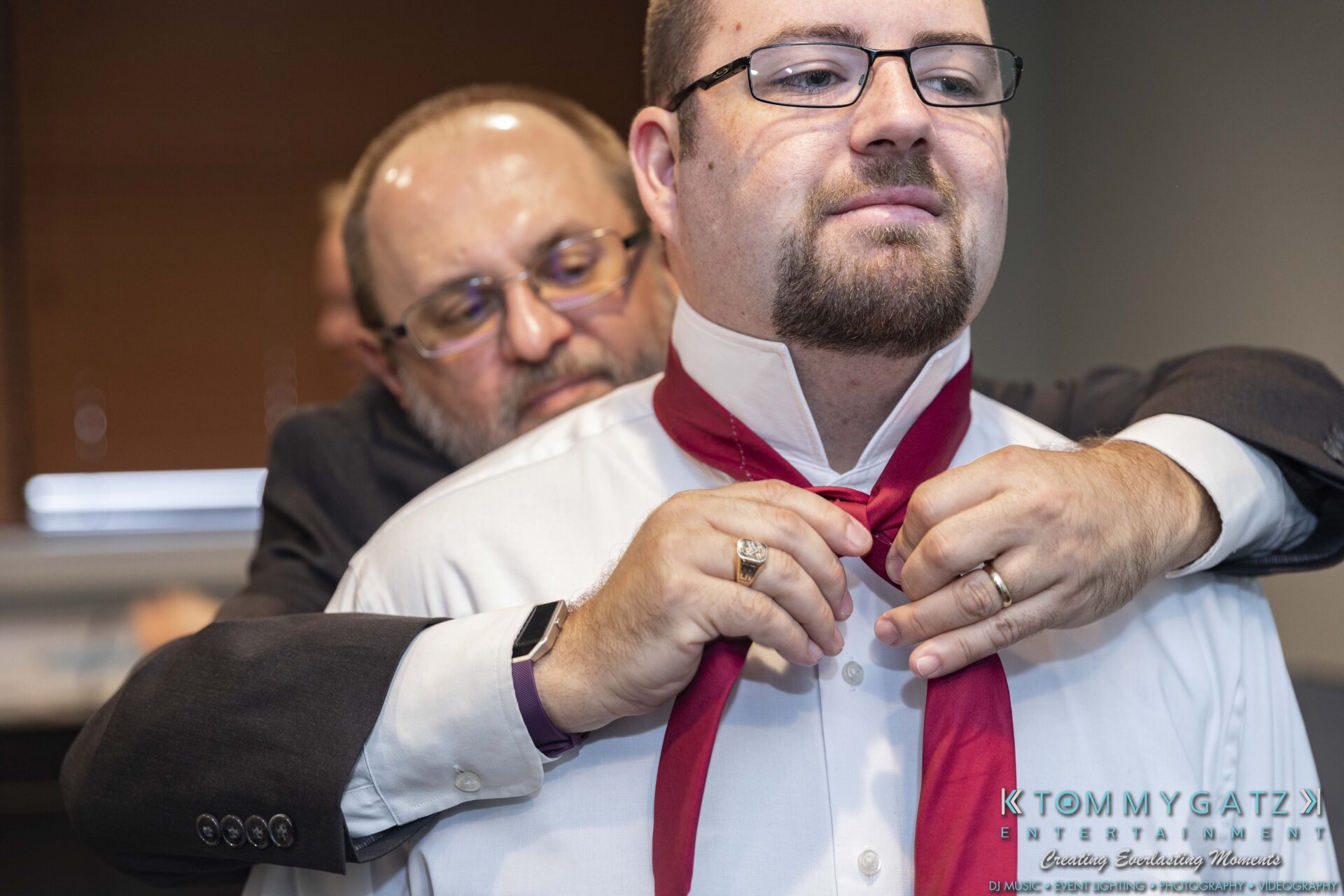 Lisa-Robert-092218-BLOG-selections-WM-6 - TOMMY GATZ ENTERTAINMENT A man helps another man adjust a red bow tie, both wearing glasses and formal attire.