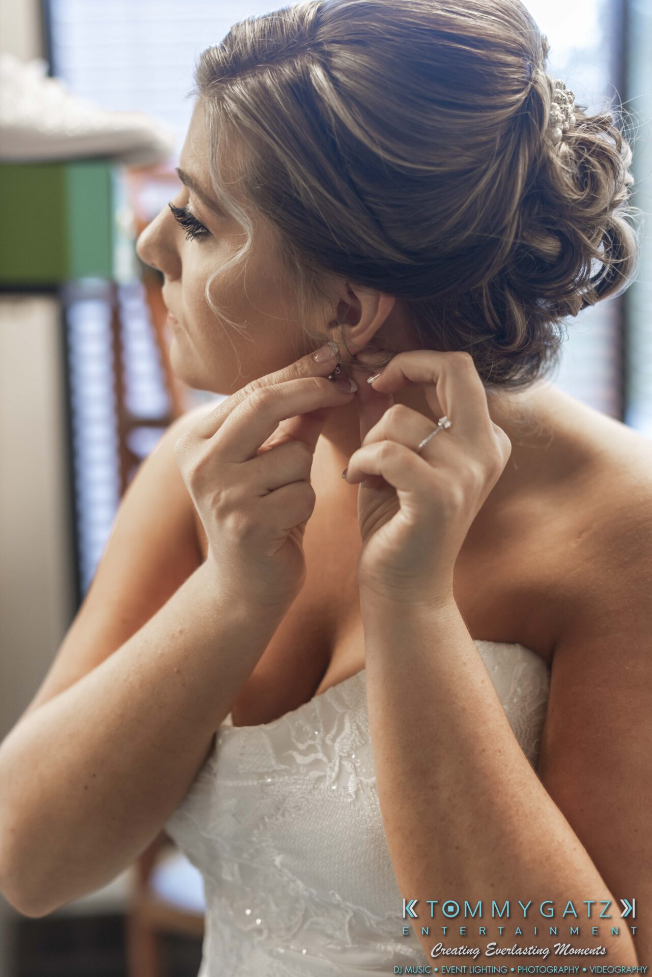 Lisa-Robert-092218-BLOG-selections-WM-7 - TOMMY GATZ ENTERTAINMENT A bride in a white strapless dress adjusts her earring in front of a window.