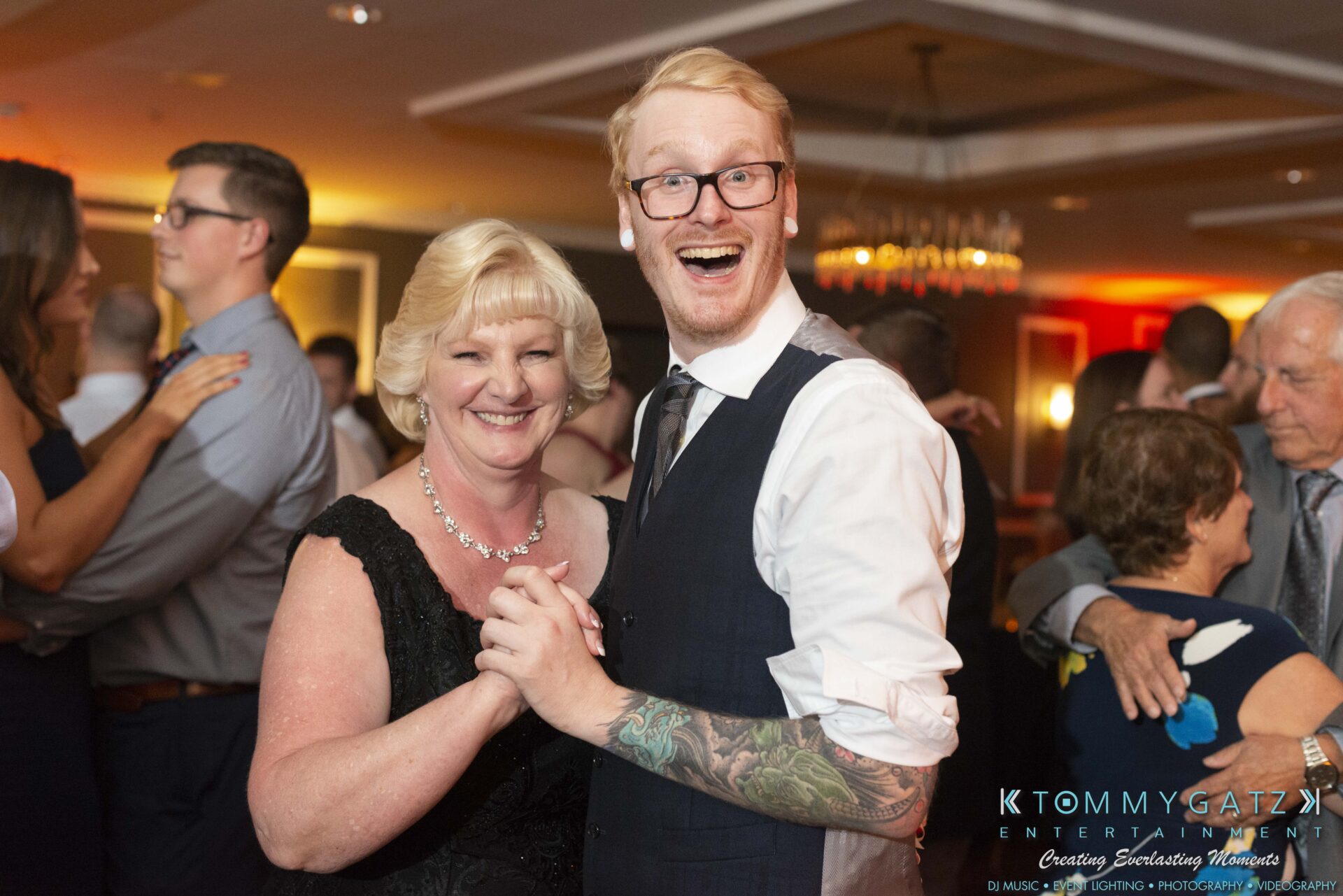 Lisa-Robert-092218-BLOG-selections-WM-98 - TOMMY GATZ ENTERTAINMENT A man and a woman smiling while dancing at an event, with other attendees in the background.