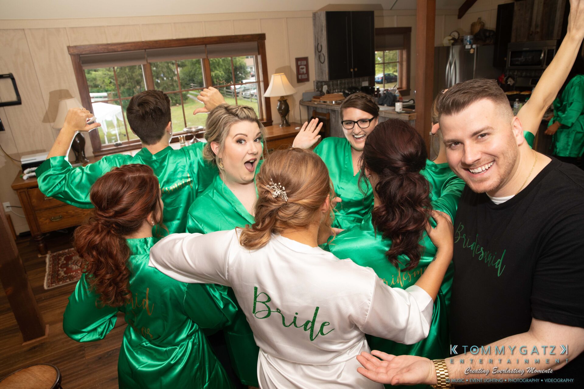 Proctor-Wedding-HIGHLIGHTS-091419-3 - TOMMY GATZ ENTERTAINMENT Group of people in matching green robes, one in white labeled "Bride," smiling and posing indoors.