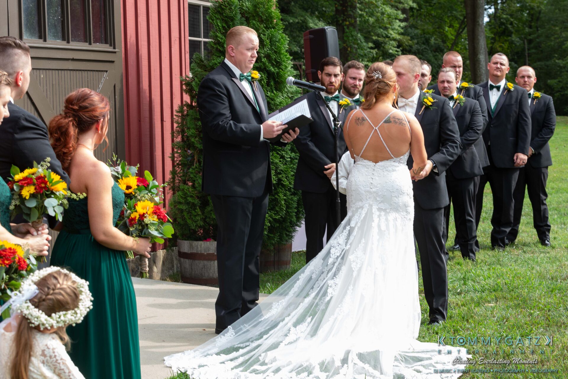 Proctor-Wedding-HIGHLIGHTS-091419-48 - TOMMY GATZ ENTERTAINMENT Bride and groom stand at an outdoor ceremony altar in front of officiant, surrounded by wedding party in formal attire.