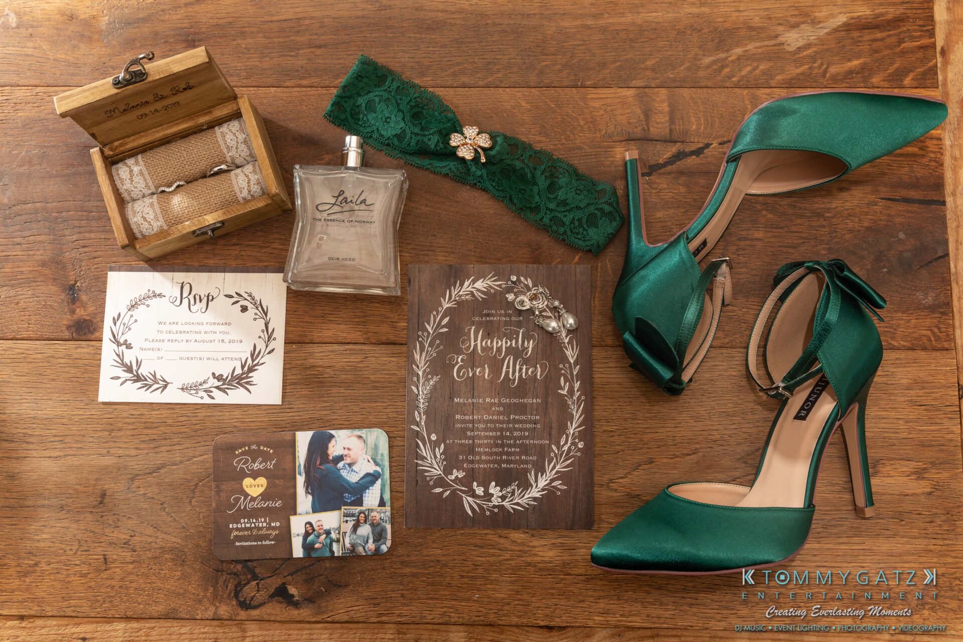 Proctor-Wedding-HIGHLIGHTS-091419-5 - TOMMY GATZ ENTERTAINMENT Wedding accessories arranged on a wooden surface include green heels, a garter, perfume, lace-wrapped bottle, jewelry, and invitations.