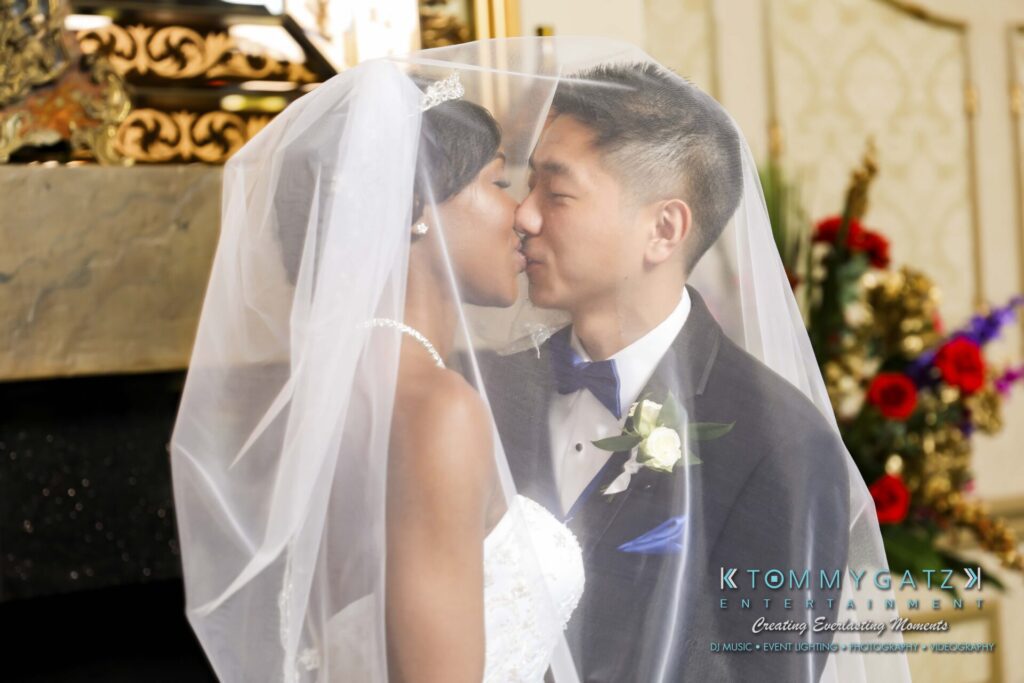 A bride and groom kiss under a veil during their wedding ceremony.