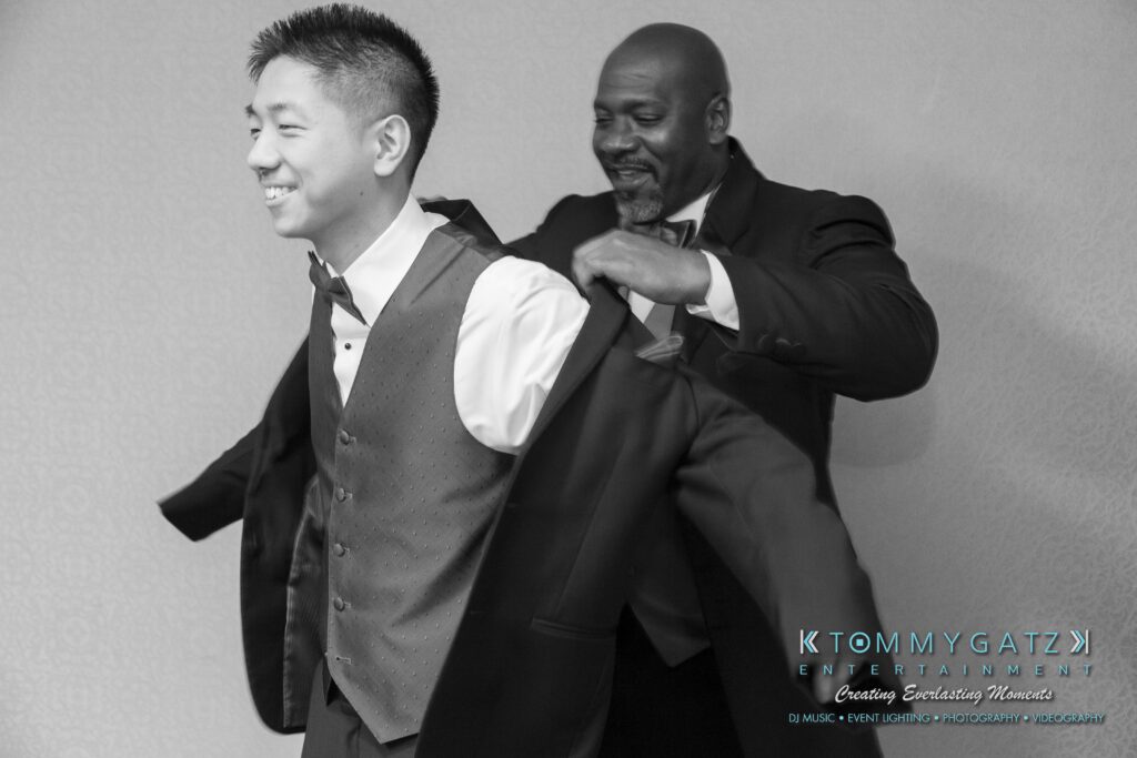 A man in a suit helps another man put on a jacket.