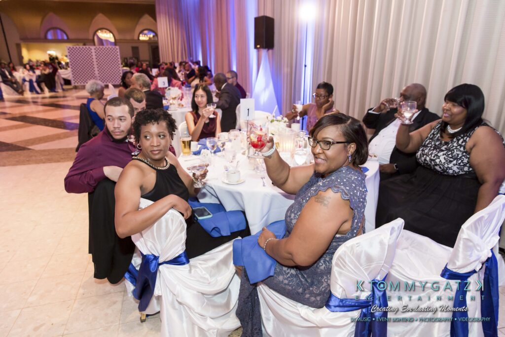 People seated at a decorated banquet table, dressed formally, some holding glasses in a toast.