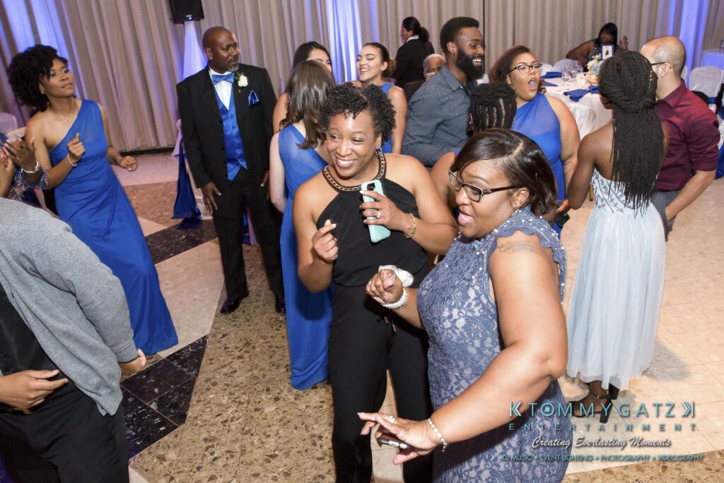 People in formal attire are joyfully dancing and socializing at an indoor event.