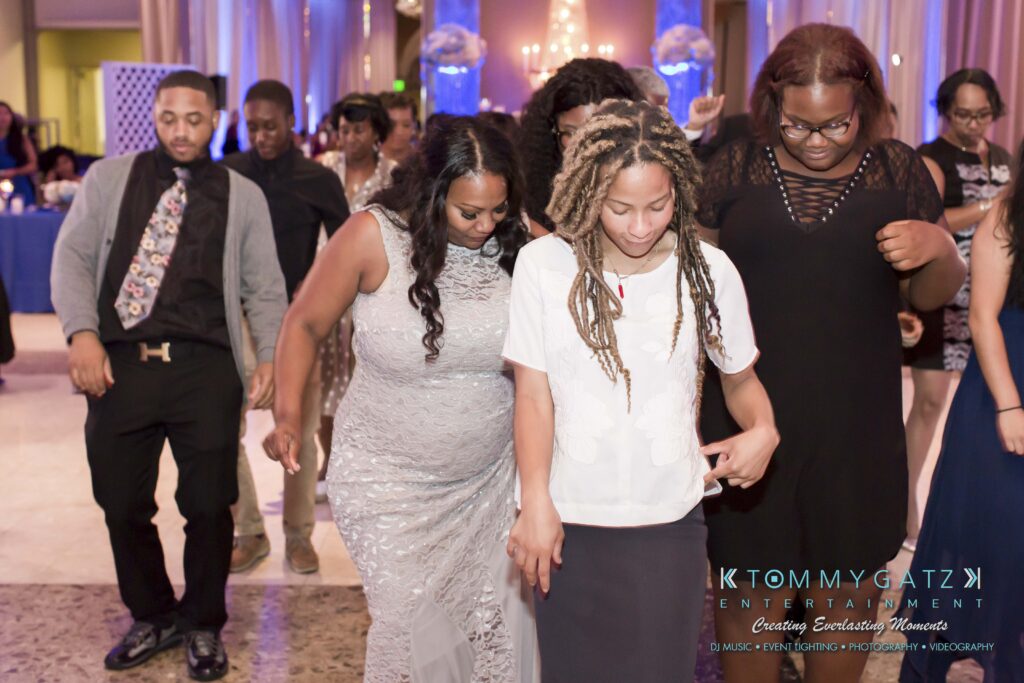 A group of people dancing together in formal attire at an indoor event.