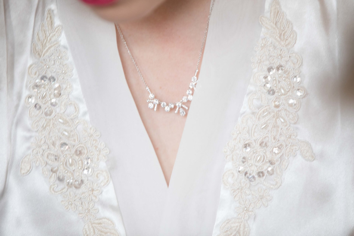 Scarlett-Michael-Wedding-Low-Res-10 - TOMMY GATZ ENTERTAINMENT Close-up of a person wearing a white embroidered garment and a silver floral necklace.