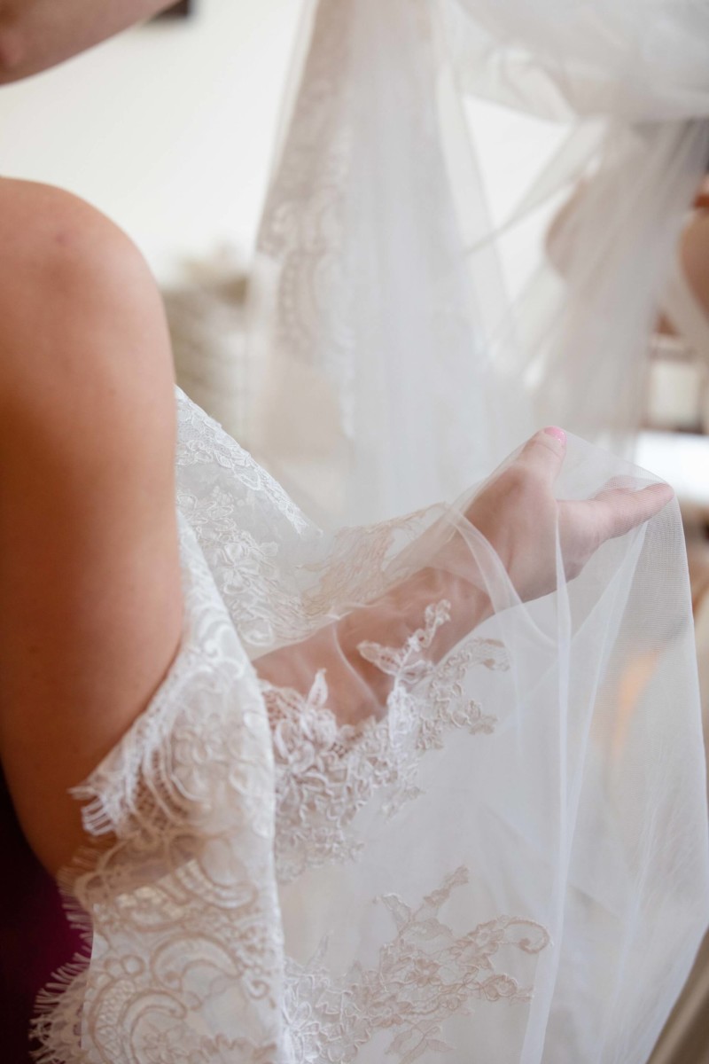 Scarlett-Michael-Wedding-Low-Res-32 - TOMMY GATZ ENTERTAINMENT A person holds delicate, white lace fabric adorned with intricate patterns.