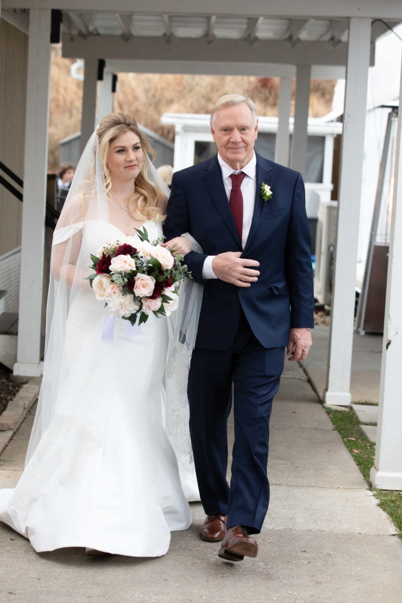 Scarlett-Michael-Wedding-Low-Res-54 - TOMMY GATZ ENTERTAINMENT A bride in a white dress and veil holds a bouquet while walking arm-in-arm with a man in a suit.