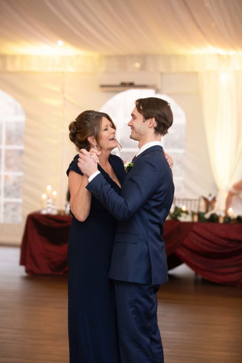 Scarlett-Michael-Wedding-Low-Res-82 - TOMMY GATZ ENTERTAINMENT A woman and a man in formal attire dance together in a warmly lit room.