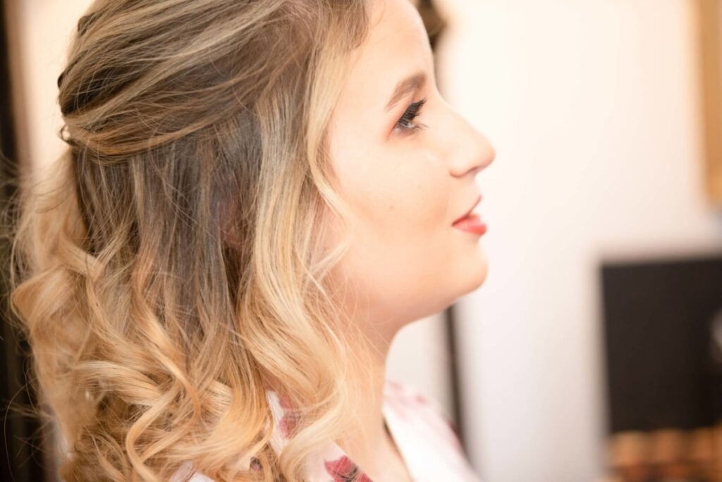 Shannon-James-Wedding-Low-Res-4 - TOMMY GATZ ENTERTAINMENT Profile view of a person with wavy blonde hair, looking to the right, wearing a white top.