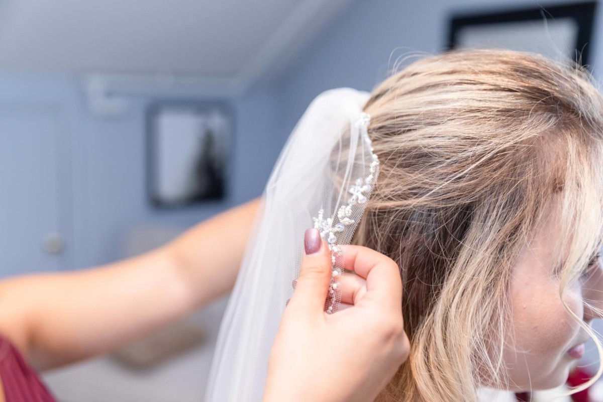 Shannon-James-Wedding-Low-Res-42 - TOMMY GATZ ENTERTAINMENT A person adjusts a beaded hair accessory on a bride's veil.