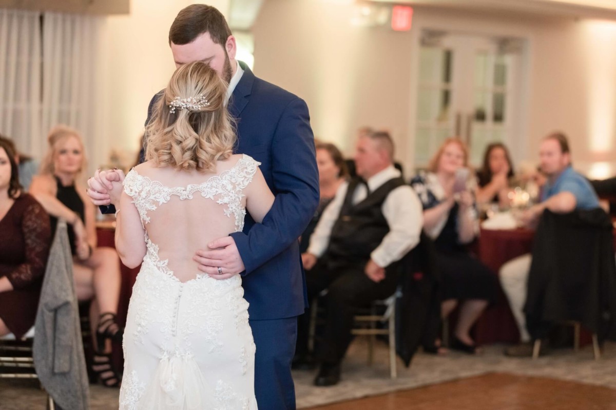 Shannon-James-Wedding-Low-Res-79 - TOMMY GATZ ENTERTAINMENT A bride and groom share a first dance at their wedding reception while guests sit and watch in the background.
