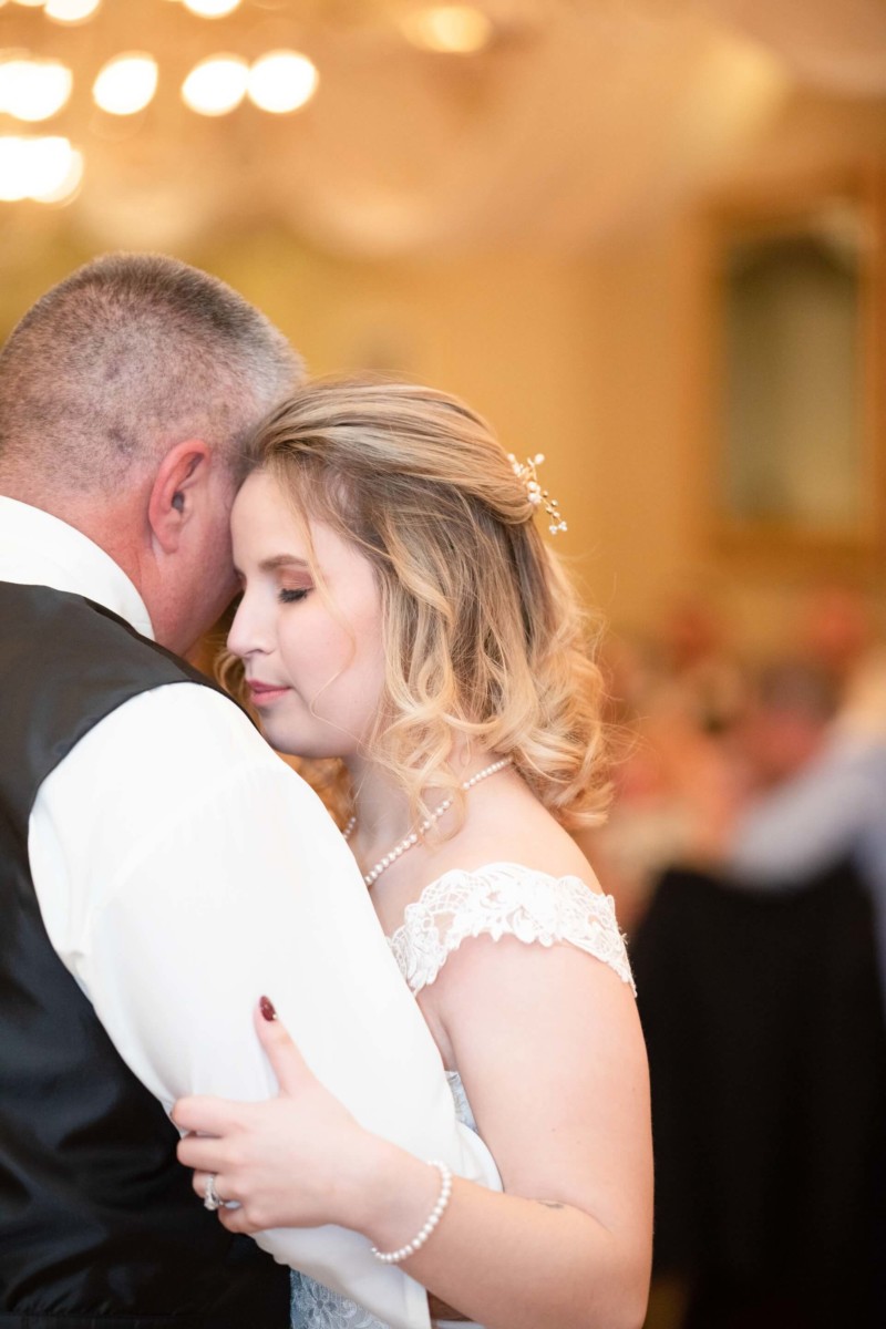 Shannon-James-Wedding-Low-Res-82 - TOMMY GATZ ENTERTAINMENT A bride and a man share a warm embrace, dancing closely at a wedding reception.